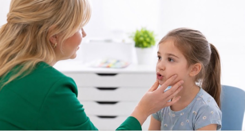 Terapia miofunkcjonalna — terapeutka ocenia pracę mięśni twarzy dziewczynki
